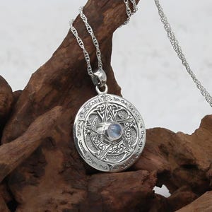 May include: Silver pendant necklace with a pentagram design and a moonstone in the center. The pendant has an inscription that reads "The Stars Among The  Boughs Of The Great Wood Are My  Guide."