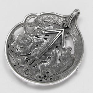 May include: Silver pendant featuring the Sagittarius zodiac sign in a Celtic knot design. The back of the pendant is engraved with the year 2009 and the artist's initials.