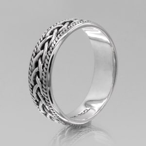 May include: A silver-colored ring with a braided design around the band. The ring has a polished, reflective surface and a detailed woven pattern. The ring is likely made of sterling silver and is a piece of jewelry.