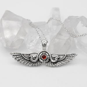 May include: A silver-toned pendant necklace featuring a winged design with intricate detailing. The pendant has a central red gemstone and is suspended from a delicate chain. The wings are spread wide, and the necklace is set against a backdrop of clear quartz crystals.