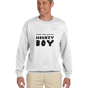 May include: A white sweatshirt with the text "Laugh while you can, MONKEY BOY" in black. The sweatshirt has a crew neck and long sleeves. The brand name "YOYODYNE" is printed in light blue.