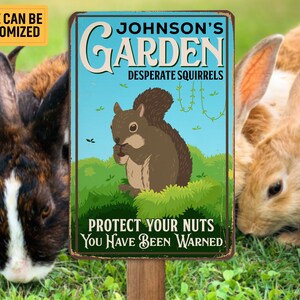 May include: A metal sign with the text "Johnson's Garden Desperate Squirrels" and "Protect Your Nuts You Have Been Warned." The sign features a cartoon squirrel and is mounted on a wooden post. Rabbits are in the background.