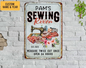 May include: A rectangular metal sign with a distressed finish, featuring the text "PAM'S SEWING ROOM" above an illustration of a vintage sewing machine, fabric, and flowers. The sign also includes the text "EST. 2023" and "MEASURE TWICE CUT ONCE OPEN 24 HOURS".