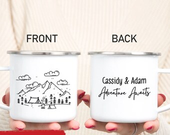 May include: White enamel camping mug with a silver rim. The front features a black line drawing of mountains, trees, clouds, a tent, and a campfire. The back of the mug says "Cassidy & Adam Adventure Awaits."