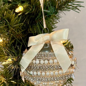 Pearlized Ornament with Rhinestone embellishments, mini bows, a Cream Satin Bow, and pearls inside the ornament.