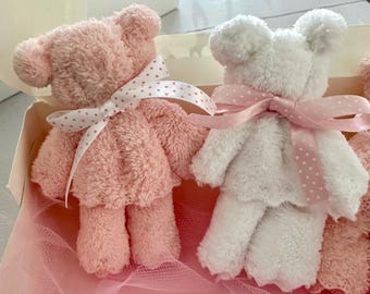 May include: Two plush teddy bears, one pink and one white, are tied with pink ribbons with white polka dots. The bears are in a gift box with pink tulle.