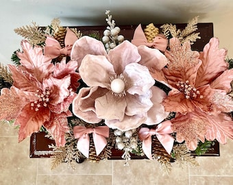 Hermoso centro de mesa navideño en oro rosa y rosa con piñas, bayas y hojas en oro rosa, champán y dorado.