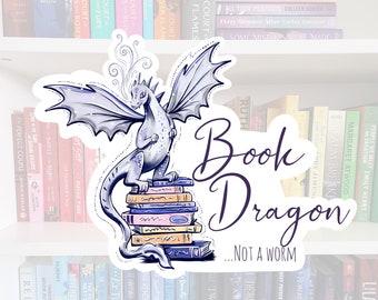 May include: A sticker featuring a purple and blue dragon with wings, perched on a stack of colourful books. The sticker has the text "Book Dragon... Not a Worm" in purple.