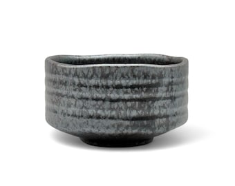 May include: A black ceramic tea bowl with a textured, rippled surface. The bowl has a wide, rounded base and a slightly flared rim.