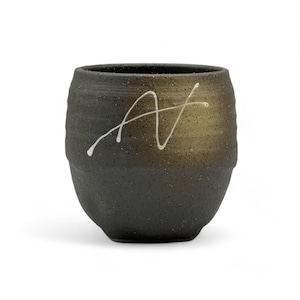 May include: A dark brown ceramic teacup with a white abstract design. The cup has a textured surface and a rounded shape.