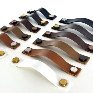 May include: Assortment of leather cabinet pulls with metal accents in various colors, including brown, black, white, and tan.