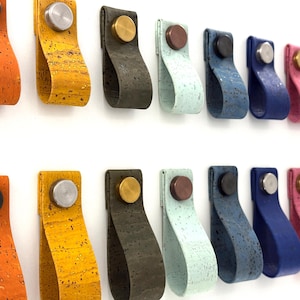 May include: Assortment of 18 cork and leather cabinet door pulls in various colours, including orange, yellow, green, blue, and pink. Each pull features a metal knob in the centre.