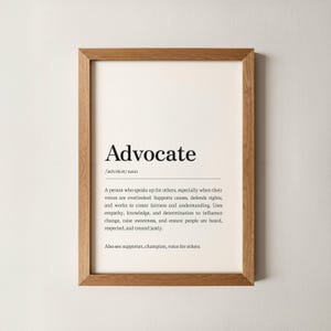 Puede incluir: Impresión enmarcada con la palabra "Advocate" en negro. La definición está debajo. El marco es de madera clara. El texto describe a un defensor.