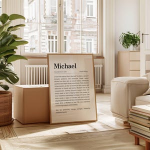 May include: A framed print with the name "Michael" in large, bold text. The print includes a definition and description of the name, set against a neutral background. The frame is a light brown color.