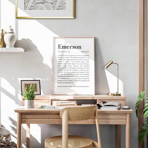 Peut inclure: Un bureau en bois clair avec une chaise assortie, une impression encadr&eacute;e avec le nom "Emerson" et une petite plante en pot. Une lampe de bureau dor&eacute;e et une image encadr&eacute;e sont &eacute;galement sur le bureau. La pi&egrave;ce a une palette de couleurs neutres.