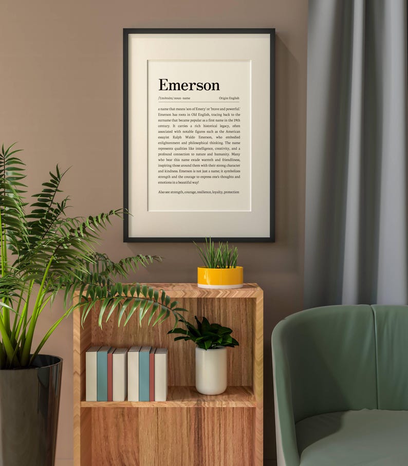 Peut inclure: Un cadre accroch&eacute; au mur avec le nom "Emerson" et sa d&eacute;finition. L'impression est dans un cadre noir et est suspendue au-dessus d'une &eacute;tag&egrave;re en bois avec des livres et des plantes. Une chaise verte et un rideau sont en arri&egrave;re-plan.