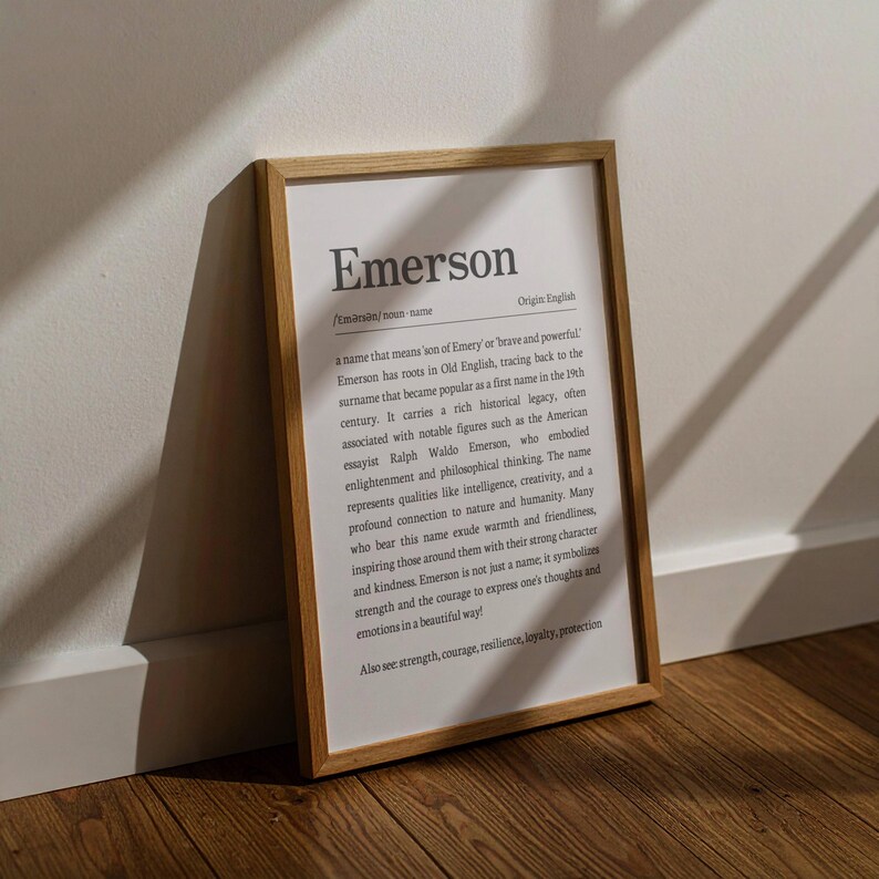 Peut inclure: Un cadre en bois clair contenant une impression avec le nom "Emerson" en noir. Le texte d&eacute;crit l'origine et la signification du nom sur fond blanc. Le cadre est pos&eacute; contre un mur blanc et un sol en bois.