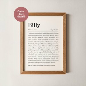 Może przedstawiać: Oprawiony wydruk z imieniem "Billy" w czarnym kolorze. Definicja imienia znajduje się poniżej. Rama jest w kolorze jasnobrązowym, a różowe kółko w lewym górnym rogu mówi "Dostępna nazwa niestandardowa".