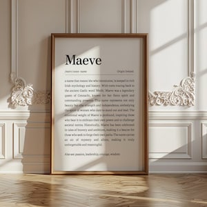 May include: A framed print with the name "Maeve" in a serif font. The text below describes the name's origin and meaning, including its connection to Irish mythology and the qualities it represents. The frame is a warm brown color.