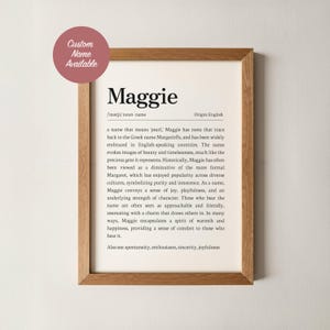 Op de afbeelding: Een houten lijst met daarin een print met de naam "Maggie". De tekst beschrijft de oorsprong en betekenis van de naam. Een ronde sticker linksboven toont "Custom Name Available".