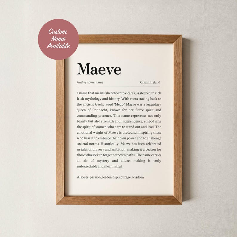 May include: A framed print with the name "Maeve" in a serif font. The print includes a definition, origin, and description of the name, with a wooden frame. A pink circle with the text "Custom Name Available" is in the upper left corner.