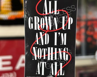Può includere: Un adesivo rettangolare con sfondo nero e testo bianco che recita ALL GROWN UP AND I'M NOTHING AT ALL. Una sottile linea rossa si snoda attraverso le lettere bianche. L'adesivo è fissato a un manico di bisturi da modellismo oro e argento.