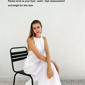 Puede incluir: Una mujer con un vestido blanco sin mangas de largo m&aacute;ximo se sienta en una silla de metal negro. El fondo es una pared blanca con el texto "Por favor, env&iacute;enos su medida de busto, cintura, caderas y altura para este art&iacute;culo."