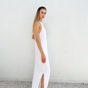 Puede incluir: Un vestido maxi blanco con escote halter y una abertura lateral. El vestido est&aacute; hecho de una tela ligera y tiene un corte holgado.