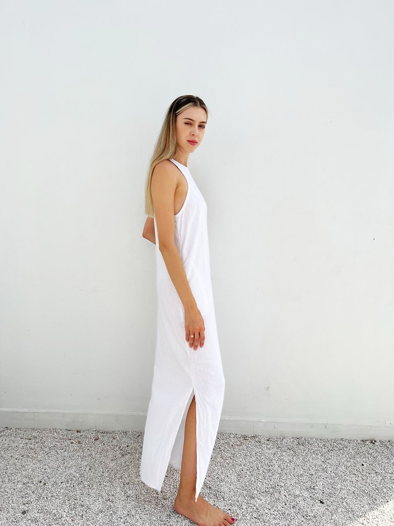 Puede incluir: Un vestido maxi blanco con escote halter y una abertura lateral. El vestido est&aacute; hecho de una tela ligera y tiene un corte holgado.
