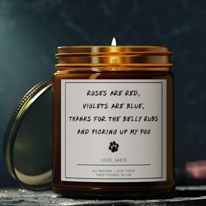 May include: A brown glass candle with a white label that reads "Roses are red, violets are blue, thanks for the belly rubs and picking up my poo. Love, Sadie. All natural, non toxic, hand poured in USA."