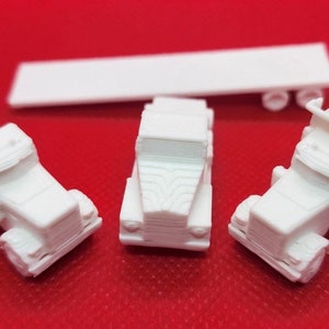 May include: Three white toy trucks, one with a cement mixer, one with a tipping body, and one with a flatbed trailer. The trucks are all facing forward and are on a red surface.