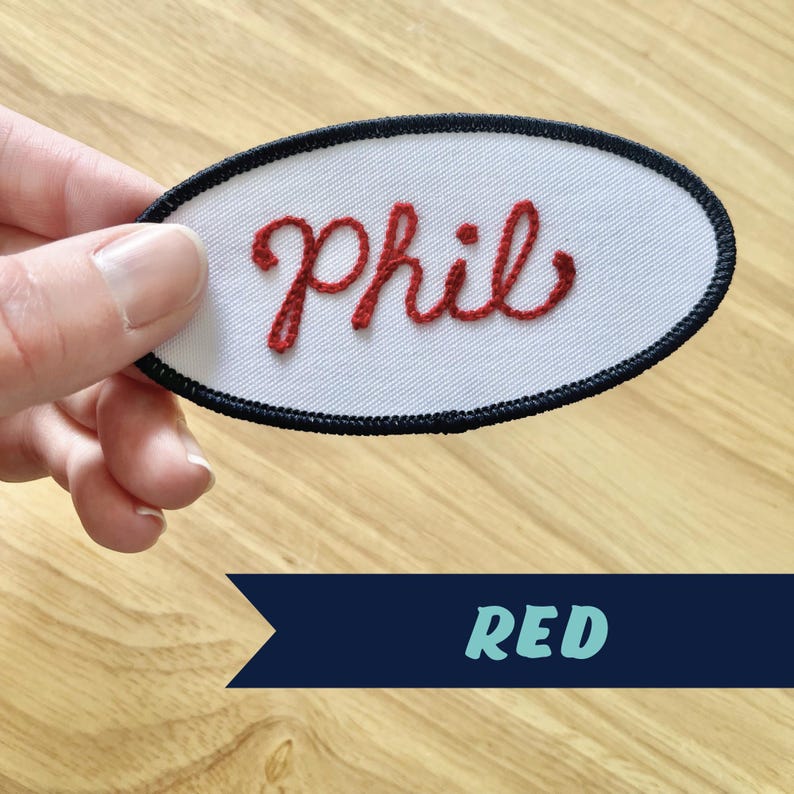 May include: Red embroidered oval patch with the name "Phil" in cursive lettering.