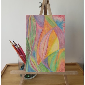 May include: Abstract art drawing on a small easel. The drawing is done in colored pencil and features a variety of colors, including pink, yellow, green, and blue.