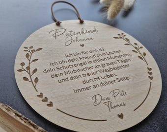 May include: A round wooden plaque with engraved text and decorative floral elements. The plaque has a leather loop for hanging. The text includes a name and a message of support and love. The wood has a natural, light brown color.