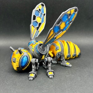 May include: A 3D-printed robotic bee model with intricate details. The bee features a yellow and black striped abdomen, a yellow head, and blue and yellow wings. The legs and other mechanical parts are gray.