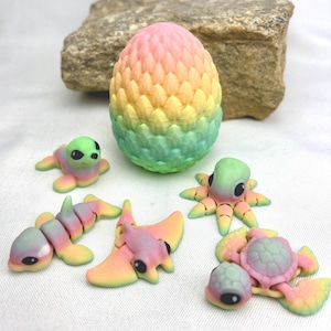 May include: A collection of colorful, miniature sea creatures and an egg-shaped object. The creatures include a seal, an octopus, a turtle, a stingray, and a segmented fish, all in pastel rainbow hues. The egg is vertically oriented, with a textured surface and a gradient of colors.