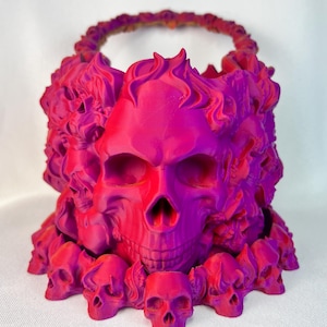 May include: A pink and purple 3D printed skull planter with a ring of smaller skulls around the base.