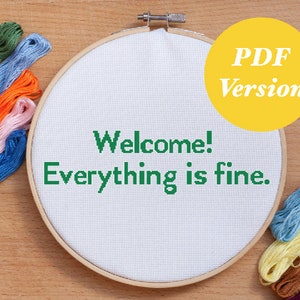 May include: A white embroidery hoop with the text "Welcome! Everything is fine." stitched in green thread.  The hoop is surrounded by colorful embroidery floss.