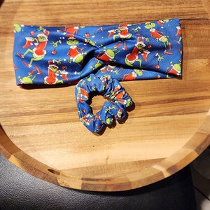 Op de afbeelding: Een blauw hoofdband met een kerstthema print van groene en rode figuren. Een bijpassende blauwe scrunchie is ook inbegrepen.
