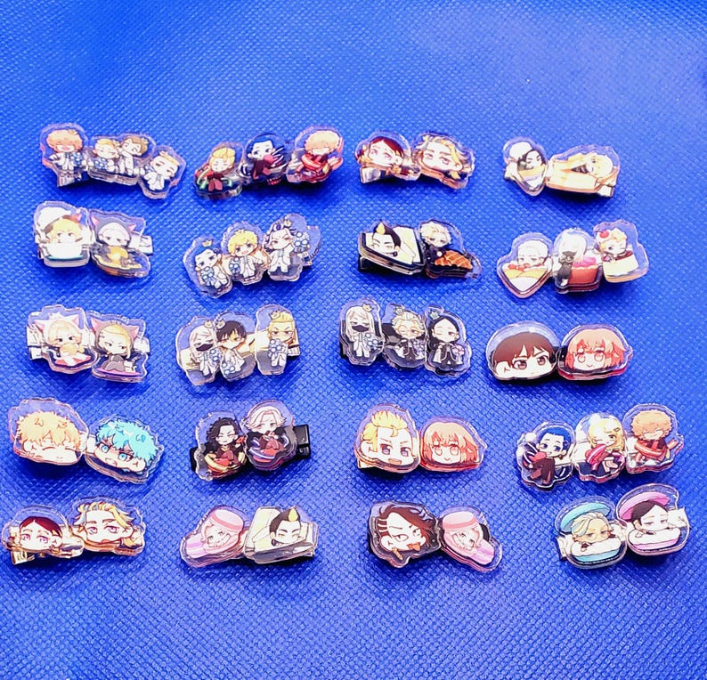 May include: A collection of 20 colorful cartoon character hair clips. The clips are made of clear plastic and feature various characters with different expressions and poses.