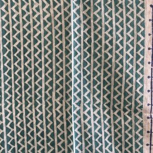 May include: A green and white fabric with a repeating chevron pattern. The fabric has a subtle texture and a slightly faded look.