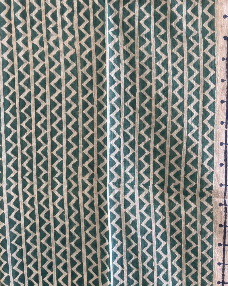 May include: A green and white fabric with a repeating chevron pattern. The fabric has a subtle texture and a slightly faded look.