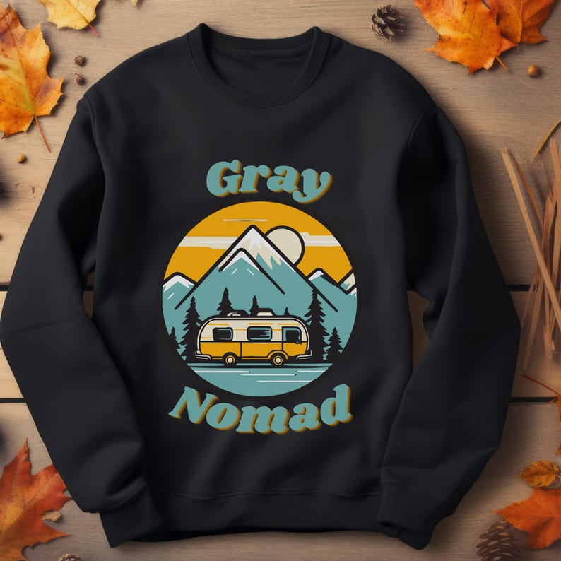 K&ouml;nnte beinhalten: Schwarzes Sweatshirt mit einer Retro-Illustration eines Wohnmobils vor Bergen. Der Text "Gray Nomad" ist in einer Retro-Schrift gedruckt.