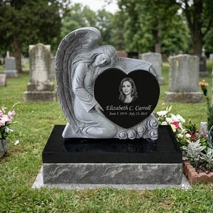 Lápida con forma de ángel esculpido, marcador de tumba de granito negro en cementerio.