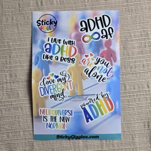 Puede incluir: Una hoja de pegatinas con varias pegatinas coloridas. Las pegatinas tienen frases como "I live with ADHD like a boss" y "Neurodiverse is the new normal". El fondo presenta figuras borrosas.