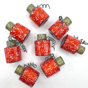 May include: A collection of eight decorative bottle stoppers. Each stopper features a cylindrical, red and white speckled body with a green top and a green wire swirl. The stoppers are arranged on a white background.