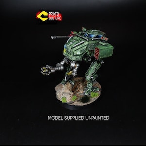 May include: A green and grey painted miniature model of a walking robot with a gun turret on top. The robot is standing on a small, brown base with green grass and dirt.