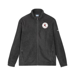 May include: A charcoal gray fleece jacket with a full zipper closure and a stand-up collar. The jacket features a circular patch on the chest with text and a red star design. The Columbia logo is visible on the sleeve.