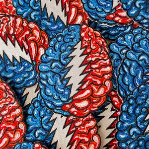May include: Close-up of a collection of colorful embroidered patches featuring a lightning bolt design with a swirling pattern. The patches are made of fabric and have a white background.