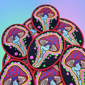 May include: A collection of embroidered patches featuring a whimsical mushroom design. Each patch has a black background with a colorful mushroom cap in shades of blue, red, and yellow. A blue figure is positioned beneath the cap, with pink and green accents.